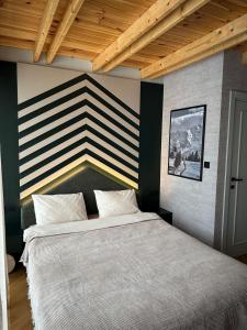 a bedroom with a large bed with a striped wall at Black Chalet in Žabljak