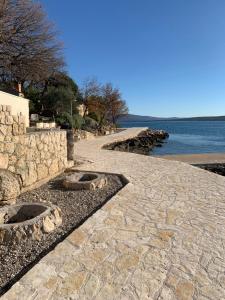 a stone path next to the ocean with a stone wall at Apartment Dubravko mit Meerblick 100 m Strand, Parking in Maslenica