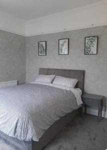 a bed in a bedroom with three pictures on the wall at Stonehouse Apartment in Mexborough +1 photo