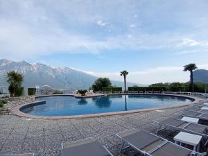 a swimming pool with chairs and mountains in the background at appartamenti Residenza 1928 in Tremosine Sul Garda