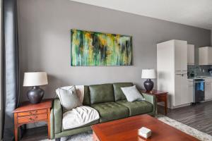 a living room with a green couch and a painting at Luxury Apt - Penthouse - King Bed Gym Pkg Pool NEW in Salt Lake City