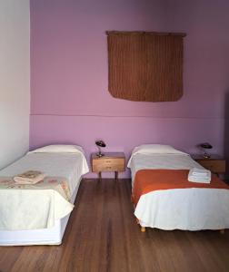 two beds in a room with purple walls and wooden floors at La Casa de Alvear - Casco Histórico in San Antonio de Areco