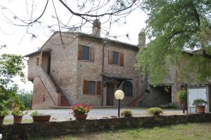 uma velha casa de tijolos com flores em frente em Agriturismo Renai e Monte em Gambassi Terme