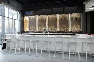 a bar with white stools in a room with windows at Aloft by Marriott Phoenix-Airport in Phoenix