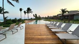 a row of chairs sitting on a deck next to a pool at teste Casa na areia da praia Peninsula de Maraú in Marau