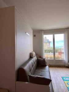 un salon avec un canapé en cuir et une fenêtre dans l'établissement Vue mer, balcon, 50m plage & village, au calme - centre ville historique, 2P pour 4 maximum, à Villers-sur-Mer
