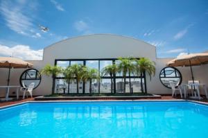 a large swimming pool with palm trees and umbrellas at The Palace Flat Moema 1210 in São Paulo
