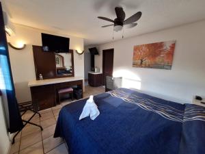 a bedroom with a blue bed with a ceiling fan at Motel Jabaloyas in Tijuana