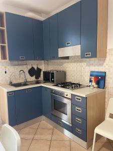 a kitchen with blue cabinets and a stove top oven at HōM - Appartamento fino a 7 posti letto comodo al centro storico, al casello A1 e alla Stazione AV in Reggio Emilia