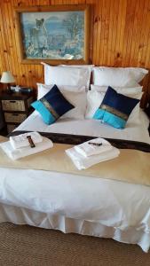 a large bed with white sheets and blue pillows at Tertia's Logcabin in Port Alfred