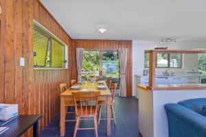 a kitchen and dining room with a table and chairs at The Retreat - Front Beach Bach in Cooks Beach