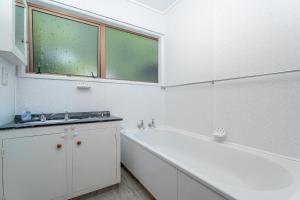 a white bathroom with a tub and a sink at The Retreat - Front Beach Bach in Cooks Beach +47 photos