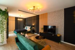 un salon avec un canapé vert et une télévision à écran plat dans l'établissement Elite Studio, à Bucarest