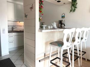 eine Küche mit weißen Schränken und weißen Stühlen an der Theke in der Unterkunft Frische Brise FeWo 01.04 in Cuxhaven
