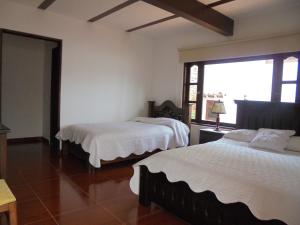 een slaapkamer met twee bedden en een groot raam bij Hospederia Villa Berenita in Villa de Leyva