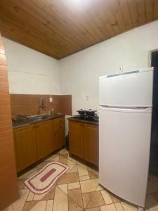 a kitchen with a white refrigerator and a sink at Casa da Vica in São Gabriel