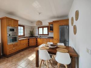 a kitchen with a wooden table and white chairs at Casa QUILI in La Caleta