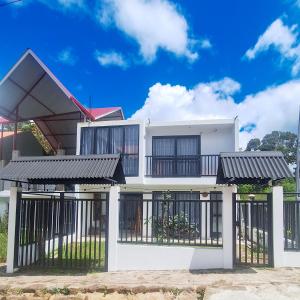 una casa blanca con puertas negras y una valla en Casa Qiru tu Refugio en Oxapampa, en Oxapampa