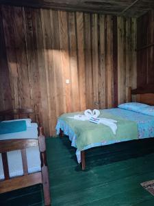 twee bedden in een kamer met houten wanden bij Santa Helena do inglês in Iranduba