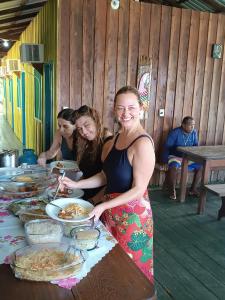 twee vrouwen die voor een tafel staan met eten bij Santa Helena do inglês in Iranduba