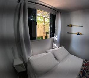 een slaapkamer met een wit bed en een raam bij Container Hospedaria Paraty in Paraty