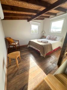 a bedroom with a bed and a chair and two windows at Los Conejos Bariloche in San Carlos de Bariloche
