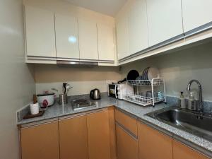 a kitchen with white cabinets and a sink at The Palladium - Modern Executive Studio in Iloilo City