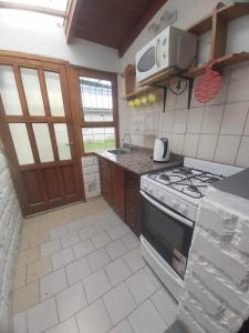 a kitchen with a stove and a microwave at Casita Las Lavandas in El Bolsón