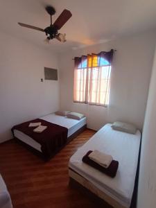 een slaapkamer met 2 bedden en een raam met een plafondventilator bij Residence Hotel Efrata Centro Itaborai in Itaboraí