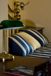 a bed with two pillows on a table with a lamp at Hotel Regina in Pinerolo