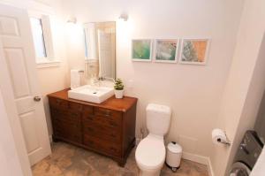 a bathroom with a toilet and a sink and a mirror at Mid-Island Getaway - Sunken Hot Tub & Deck - Close to Beach - Modern in Nanaimo +25 photos