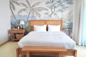 a bedroom with a large bed with a tropical wallpaper at The Beach Bangsaen by Thanthita next to Wonnapa beach FREE DISNEY PLUS in Bangsaen