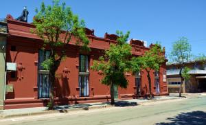 a red building with trees in front of a street at Hotel Posada La Comandancia in Melo