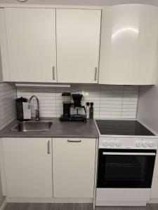a kitchen with white cabinets and a sink and a stove at Central City Apartment in Svolvær +20 photos