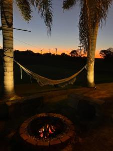 a hammock hanging between two palm trees next to a fire at Pousada Bonetti Quarto 1 in Santa Rosa +2 photos