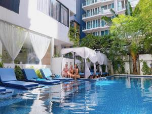 un grupo de personas sentadas en sillas junto a una piscina en Home Chic Hotel, en Phnom Penh