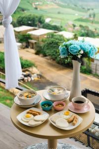 a table with plates of food and a vase with flowers at เดอะซัน แกลมปิ้ง in Ban Mae Na