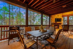 a screened in porch with a table and chairs at Merlot Mountain By The Cohost Company in Broken Bow