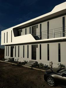 a white building with a car parked in front of it at Departamento Apolo in Jamay