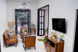 un salon avec une télévision, une table et des chaises dans l'établissement Seruni Garden - Guesthouse Bandung, à Bandung