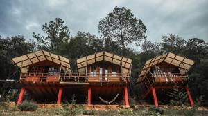 a group of three houses with red posts at Eko Aldea Kolybry in San Joaquín