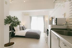 a bedroom with a bed and a kitchen with a sink at 5C Guest House INFINITY in Naha