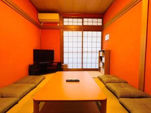 a living room with orange walls and a wooden table at Koguma Shizuka in Osaka