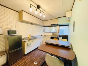 a small kitchen with a wooden table and a refrigerator at Koguma Shizuka in Osaka