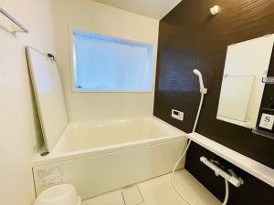 a bathroom with a tub and a toilet and a window at Koguma Shizuka in Osaka +10 photos