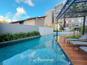a swimming pool with chairs on a wooden deck at Vert House Bessa - Miramar Hospedagens in João Pessoa