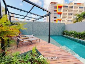 a deck with chairs and a swimming pool on a building at Vert House Bessa - Miramar Hospedagens in João Pessoa
