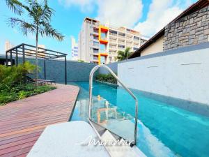 a swimming pool with a wooden walkway next to a building at Vert House Bessa - Miramar Hospedagens in João Pessoa