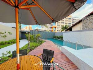 a wooden deck with a table and an umbrella at Vert House Bessa - Miramar Hospedagens in João Pessoa +123 photos