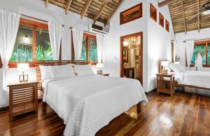 two beds in a bedroom with white walls and wooden floors at Copa De Arbol Beach & Rainforest Resort in Drake